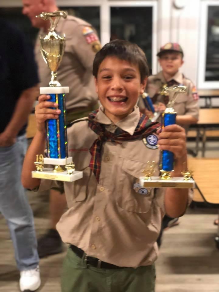Young Jack holding two trophies in his Scout uniform